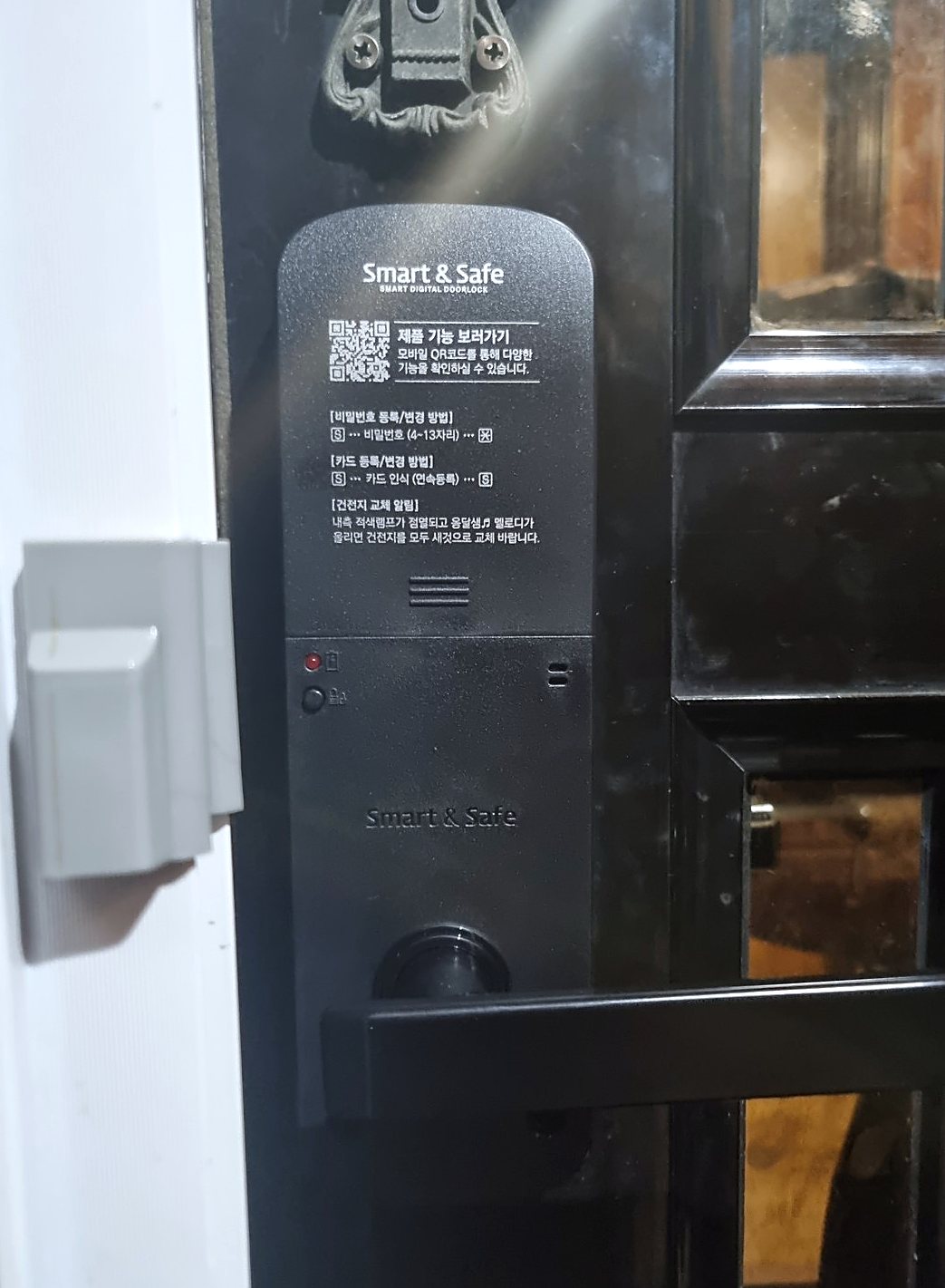 영등포구 영등포동 출장 — 짙은 색 문에 달린 검은 레버형 도어락, 앞면에 켜진 붉은 불빛과 가로로 놓인 검은 레버